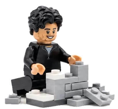 Lego figure of Jacob, smiling, building with grey bricks.